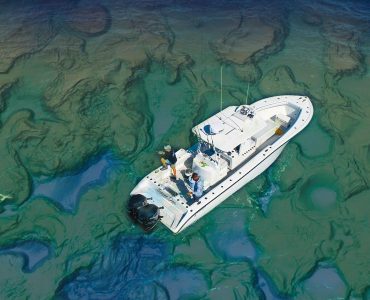 Vista aérea de un barco de pesca navegando sobre un fondo marino con relieve muy detallado, ilustrando la importancia de interpretar correctamente las estructuras del fondo con cartografía de alta resolución.