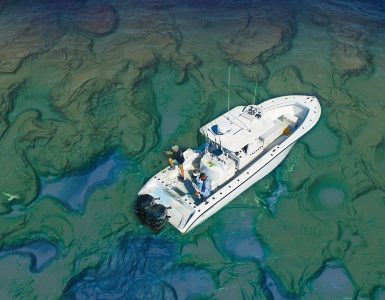 Vista aérea de un barco de pesca navegando sobre un fondo marino con relieve muy detallado, ilustrando la importancia de interpretar correctamente las estructuras del fondo con cartografía de alta resolución.
