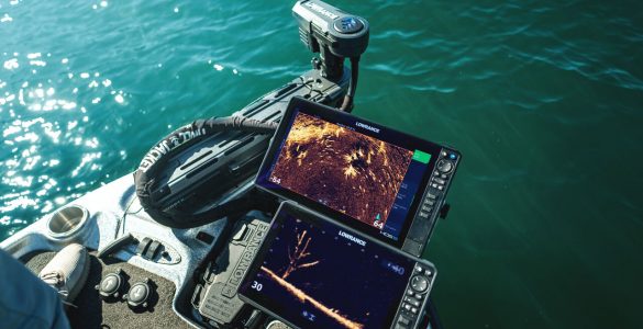 Vista desde la proa de una embarcación de pesca mostrando dos pantallas Lowrance operando en tiempo real con el sonar ActiveTarget 2 XL. En las pantallas se aprecian vistas detalladas del fondo y un árbol sumergido, junto al motor eléctrico desplegado en el agua.