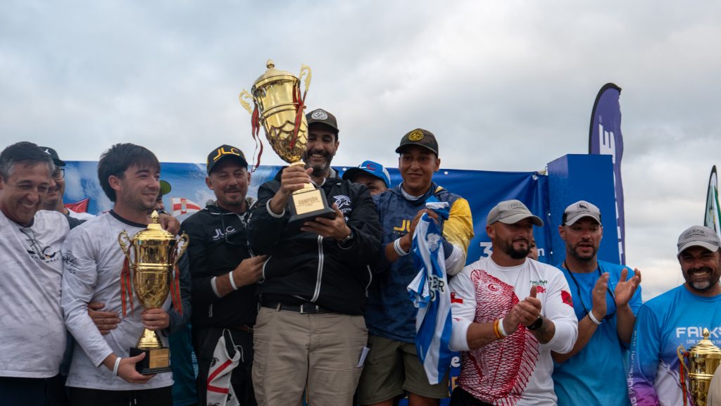 El ganador principal levanta el trofeo de campeón de la Copa del Estrecho 2025, rodeado de su equipo en el podium.