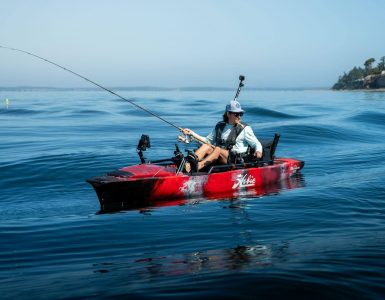 Pescador navegando en kayak Hobie equipado con caña de pesca y accesorios en mar abierto