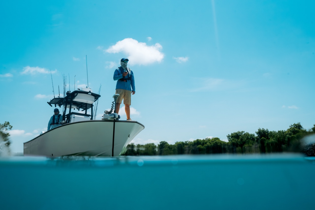 Hombre encima de un barco de día, con el motor lowrance recon al frente