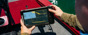 Pescador interactuando con la sonda GPS plotter Lowrance Eagle Eye 9 en tiempo real, a bordo de un barco, visualizando datos de sonda y cartografía.
