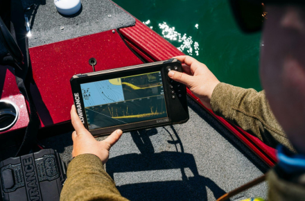 Pescador interactuando con la sonda GPS plotter Lowrance Eagle Eye 9 en tiempo real, a bordo de un barco, visualizando datos de sonda y cartografía.